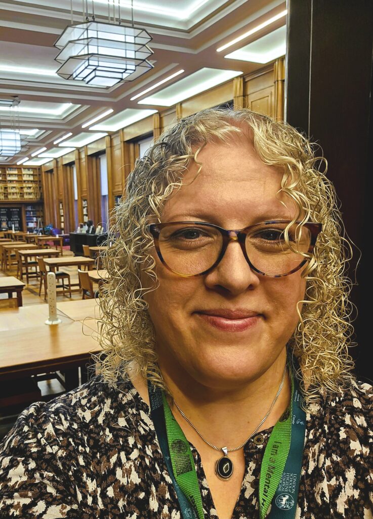 Photo of a smiling woman with a library in the background