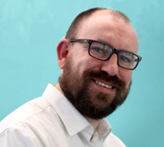 Photo of Steve Briggs, a man with a beard and glasses smiling